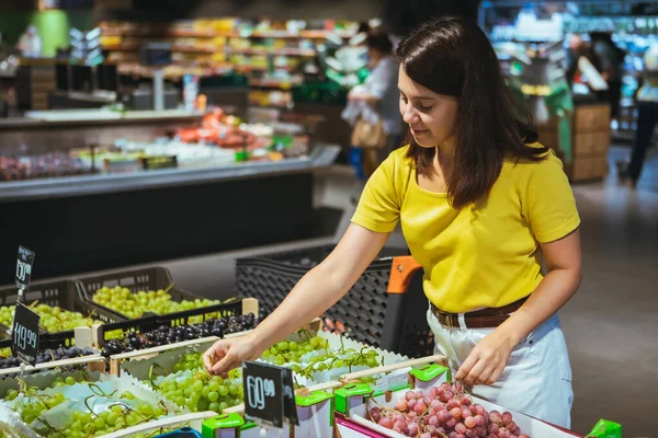 Kvinna som köper druvor i butik — Stockfoto