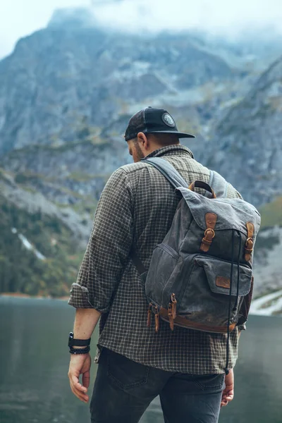 Человек с рюкзаком на озере в горах туристическая концепция — стоковое фото