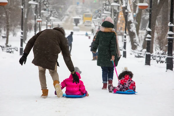 Niños deslizándose en la colina de invierno en el parque de la ciudad — Foto de Stock