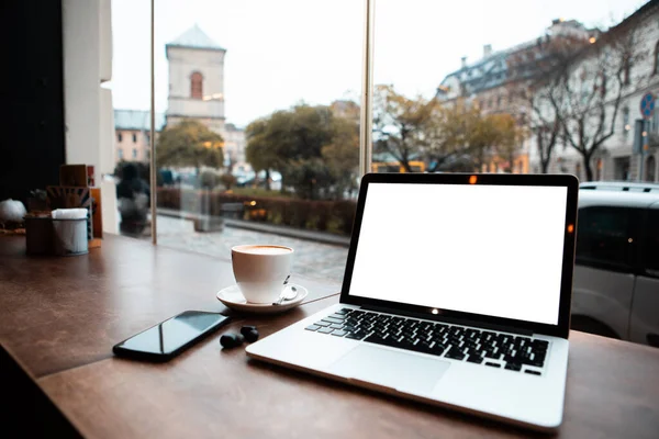 Laptop Fehér Képernyővel Kávézó Asztal Ablaka Közelében Kilátás Városra — Stock Fotó