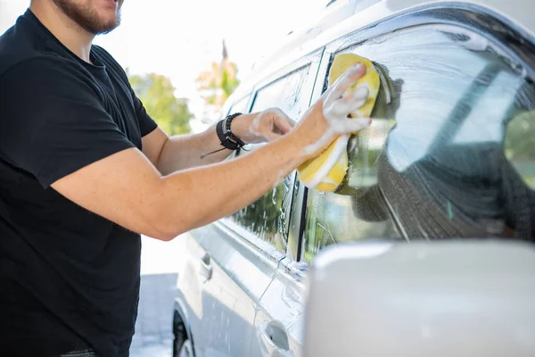 黄色いスポンジで車を掃除する男 洗車のコンセプトだ コピースペース — ストック写真