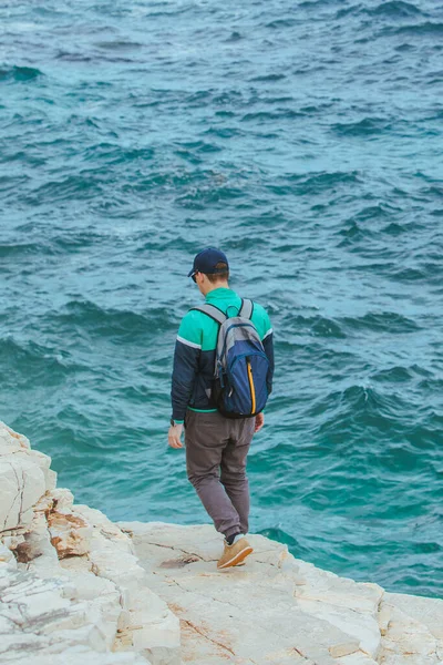登る男だ 岩の縁だ 海の景色を楽しむ 旅行のコンセプト — ストック写真