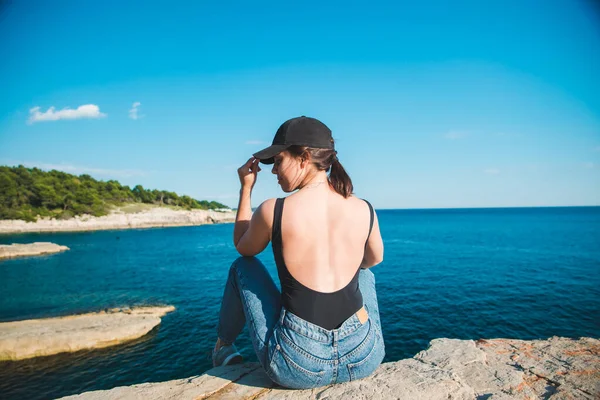 年轻漂亮的女人坐在悬崖上观看夏天的海上度假 — 图库照片