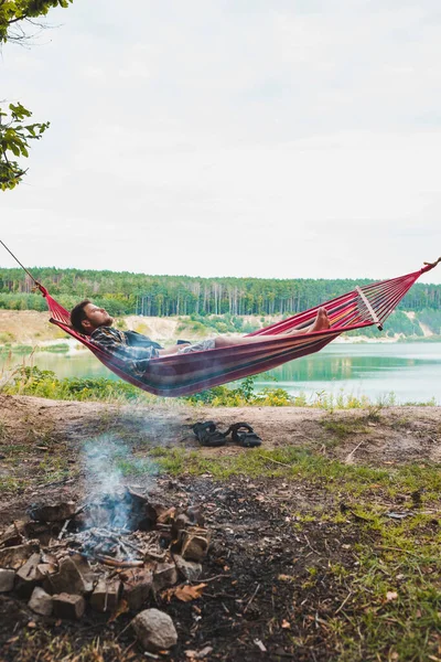 Mann Liegt Auf Hängematte Seestrand Der Nähe Von Lagerfeuertourismus Konzept — Stockfoto