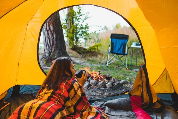 Frau liegt in gelbem Zelt und blickt auf Lagerfeuer — Stockfoto