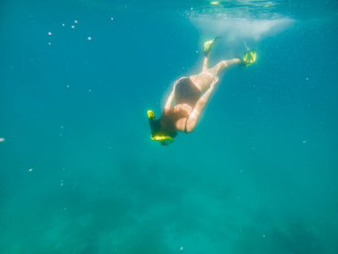 Şnorkel maskeli bir kadın ve deniz altında yüzgeçli yaz tatili