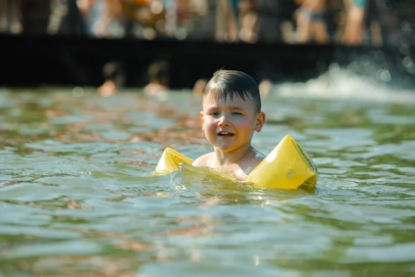 little toddler kid swimming in lake with inflatable arms aids support summer lake