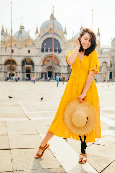 stunning woman in yellow dress walking by city square basilica saint marco on background Venice, Italy