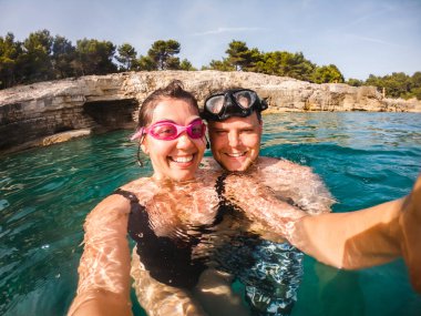 Dalış maskeli çift yaz tatilinde deniz suyunda selfie çekiyor.