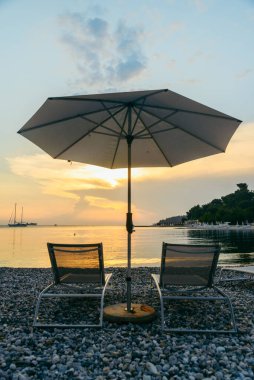 Güneş pansiyonları ve şemsiyeli deniz sahili manzarası. Boşluğu kopyala