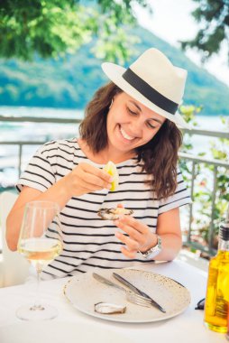 Güneşli yaz havasında açık hava restoranında istiridye yiyen bir kadın. Yaşam biçimi