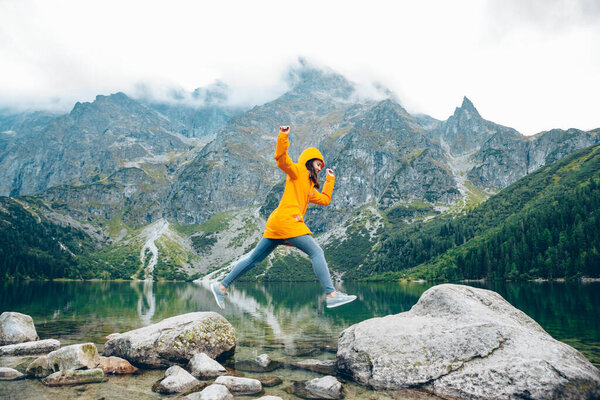 woman jumping from rock at beach lake in mountains tatra national park