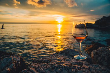 Gün batımında Rocky Sea Beach 'te bir bardak şarap. kopyalama alanı. yaz tatili