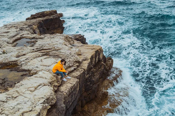 Uçurumun Kenarında Oturan Kadın Denizin Büyük Dalgalarını Izliyor — Stok fotoğraf