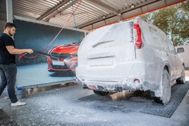 Güçlü bir adam yaz zamanı dışarıda arabasını yıkıyor.