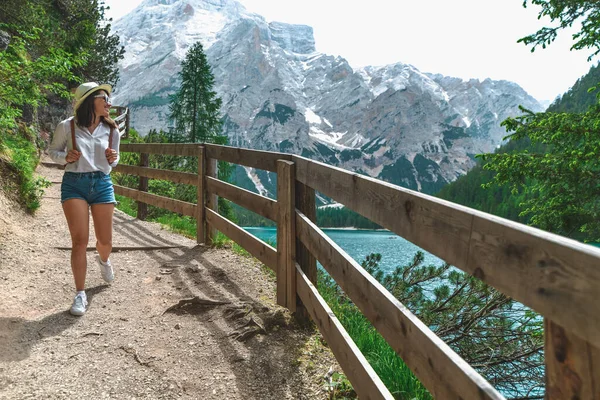 山の中の湖の周りの歩道を歩くバックパックを持つハイカーの女性 コピースペース — ストック写真