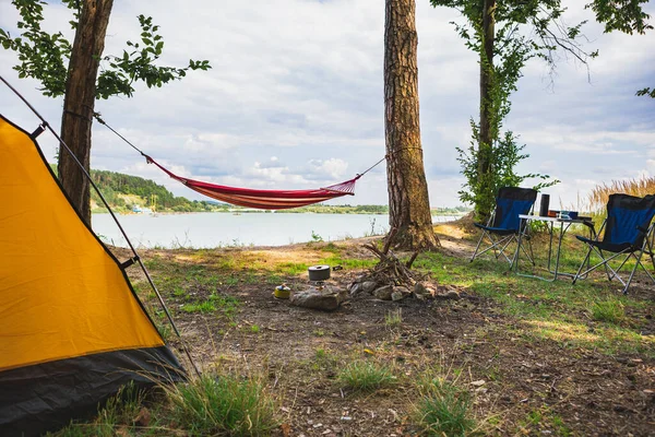 view of camping near lake with hammock between trees copy space