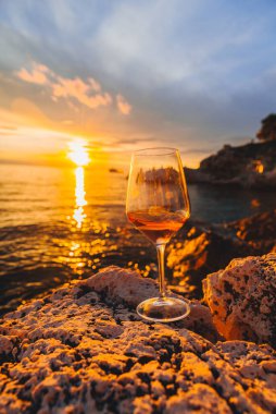 Gün batımında Rocky Sea Beach 'te bir bardak şarap. kopyalama alanı. yaz tatili