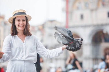 Beyaz şapkalı kadın Venice City Meydanı San Marco 'da güvercinlerle eğleniyor.