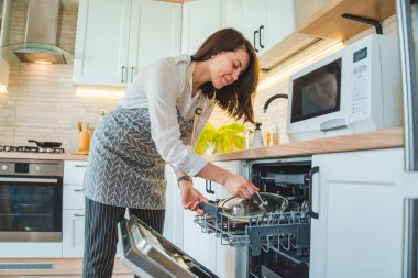 Bulaşık makinesine bulaşık koyan genç ve güzel bir kadın. yerel yaşam tarzı