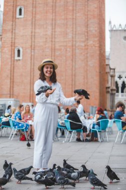 Beyaz şapkalı kadın Venice City Meydanı San Marco 'da güvercinlerle eğleniyor.