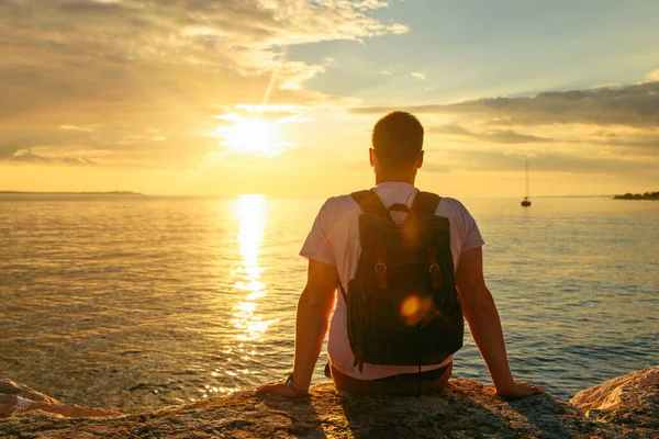 Sırt çantalı bir adam denizde günbatımının tadını çıkarıyor. kopyalama alanı. yaz tatili
