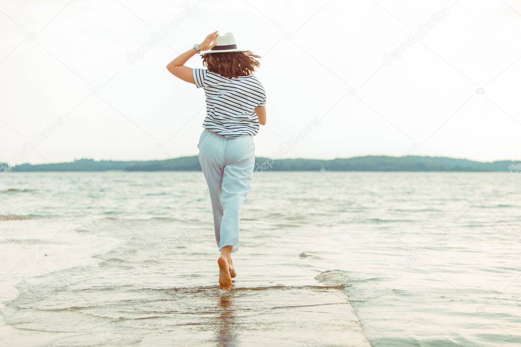 woman in white clothes walking by sea beach summer time