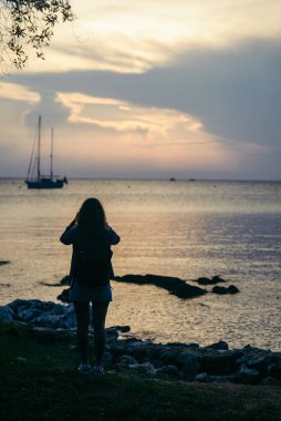 Gün batımında körfezdeki yatın fotoğrafını çeken kadın. kopyalama alanı. yaz zamanı