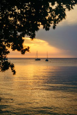 Deniz koyunda günbatımı ve arka planda yatlar. Boşluğu kopyala