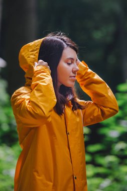 Sarı yağmurluklu kadın yağmurlu ormanda yürüyor. Dikiz aynası. kopyalama alanı. Büyük dünyadaki küçük insanlar.