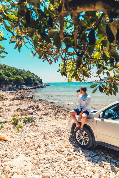 男子与咖啡杯站在汽车附近在海上夏季海滩度假的概念 — 图库照片