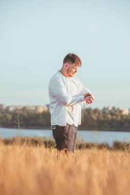Adam buğday tarlasında gün batımında yürüyor. arkaplanda göl