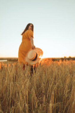 Sarı elbiseli kadın buğday tarlasında yürüyor. yaz zamanı