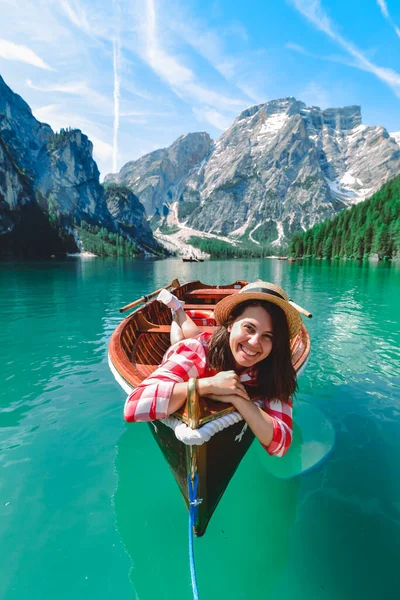 woman sitting in big brown boat at lago di braies lake in Italy. summer vacation