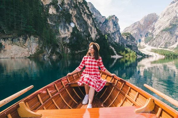 woman sitting in big brown boat at lago di braies lake in Italy. summer vacation