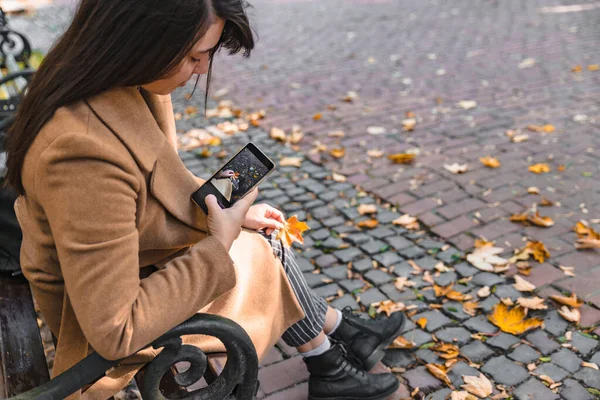 Woman taking picture of yellow maple leaf — Stock Photo, Image