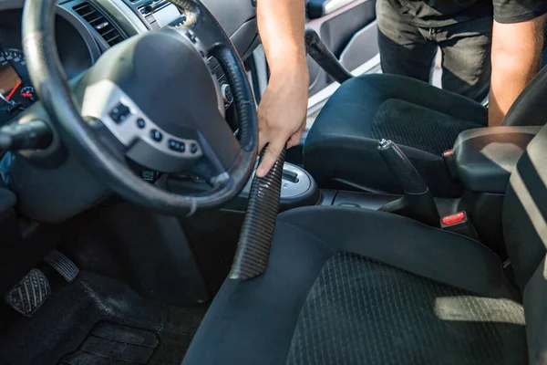 man cleaning inside car with vacuum cleaner seats