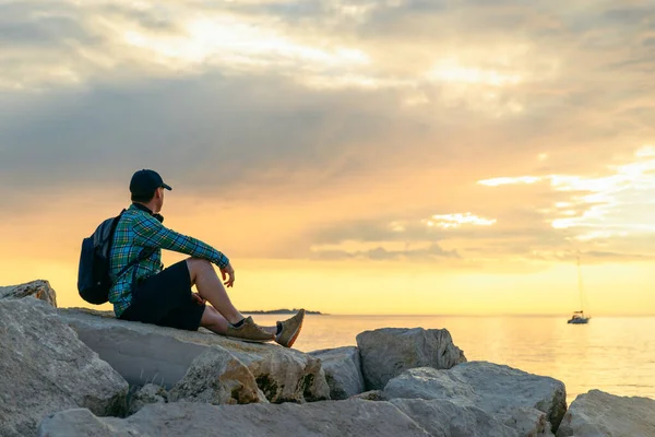 Sırt çantalı bir adam gün batımını seyrediyor ve müzik dinliyor. Boşluğu kopyala