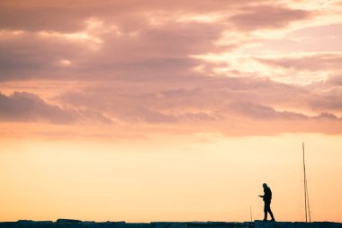 Pembe günbatımı gökyüzünde insan silueti. Boşluğu kopyala