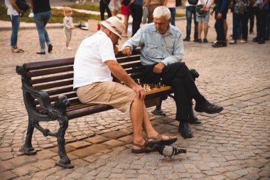 Lviv, Ukrayna - 18 Eylül 2018: İki yaşlı adam yazın şehir bankında açık havada satranç oynuyor.
