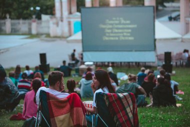 Halk parkındaki açık hava sinemasında kamp sandalyesinde oturan çift.