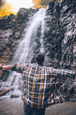 Yürüyüş yapan adam sonbahar şelalesine bakıyor. Kopya alanı
