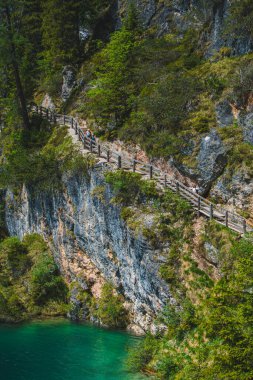 Altında mavi su bulunan kaya dağlarındaki patika manzarası. yaz zamanı