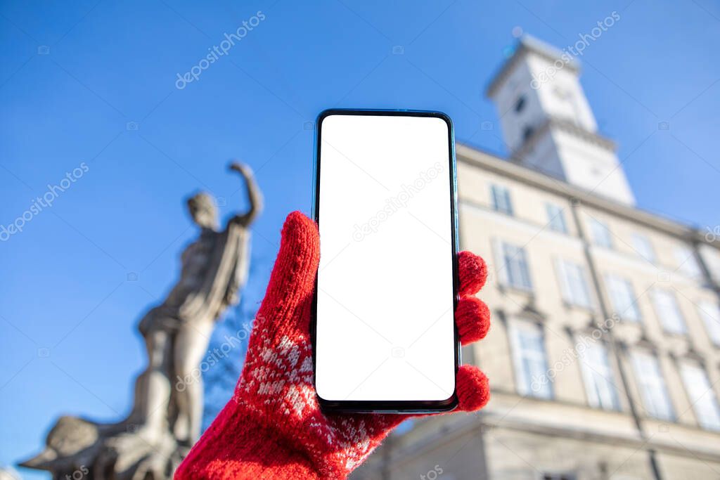 woman hand in red gloves holding phone with white screen lviv city hall on background copy space travel concept