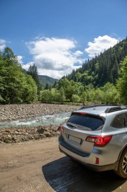 Nehir kenarındaki dağlarda bir arazi aracı. Yolculuk konsepti. off road