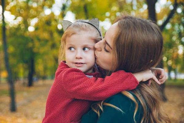 Sonbahar kenti parkında anne kız kucaklaşması.