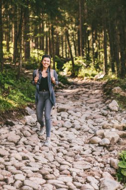 Sırt çantalı bir kadın ormanda taş patika gezisi konseptiyle yürüyor.