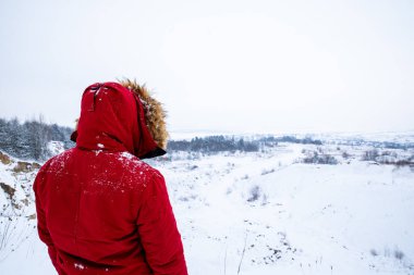 Kırmızı kışlık giysiler içinde kar tarlasına bakan birini arkadan görmek. Yalnız.