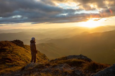 Dağların tepesinde gün batımını seyreden adamın silueti. yürüyüş kavramı