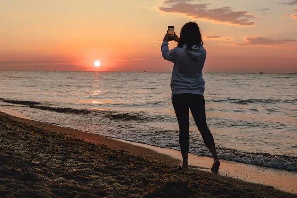 Deniz sahilinde gün batımını seyreden bir kadın. Boşluğu kopyala.